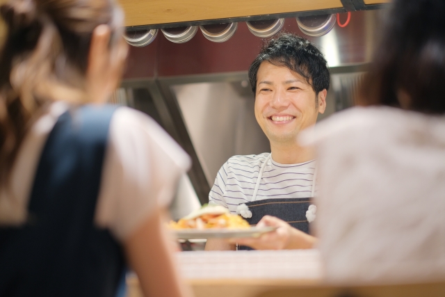 飲食店で料理を提供する男性